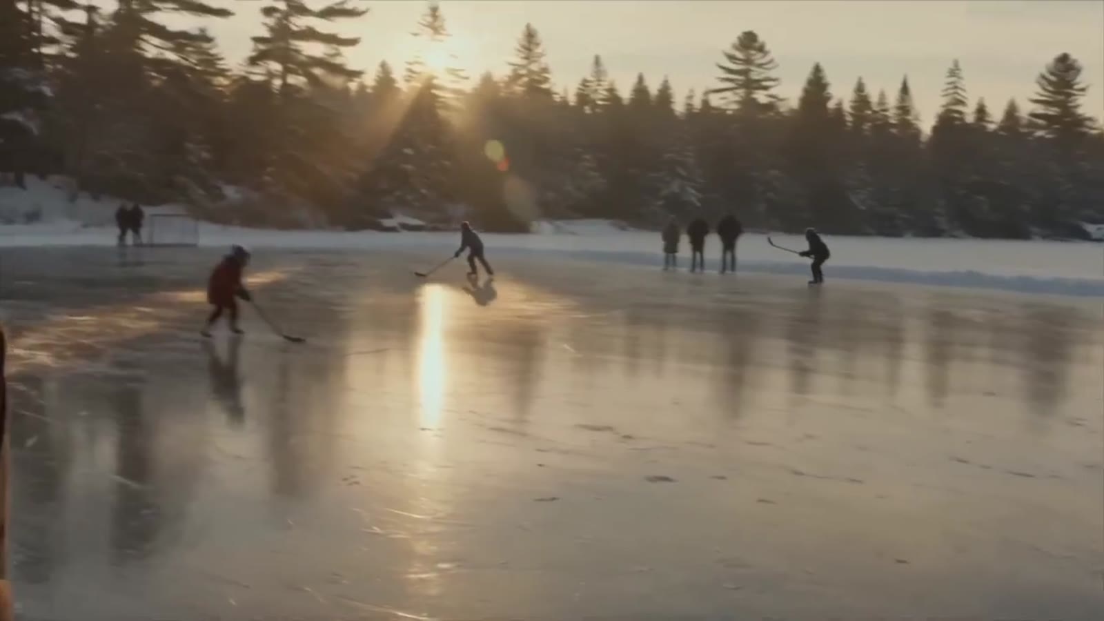 Kids playing hockey on a frozen pond at sunrise