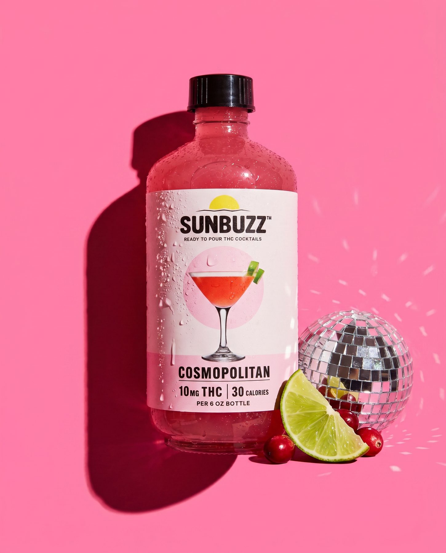 SunBuzz Cosmopolitan bottle on pink with a disco ball